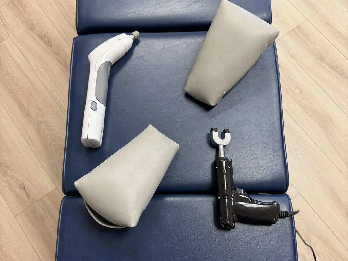 Hand-held adjusting instruments and support wedges on a treatment table at Scott Chiropractic