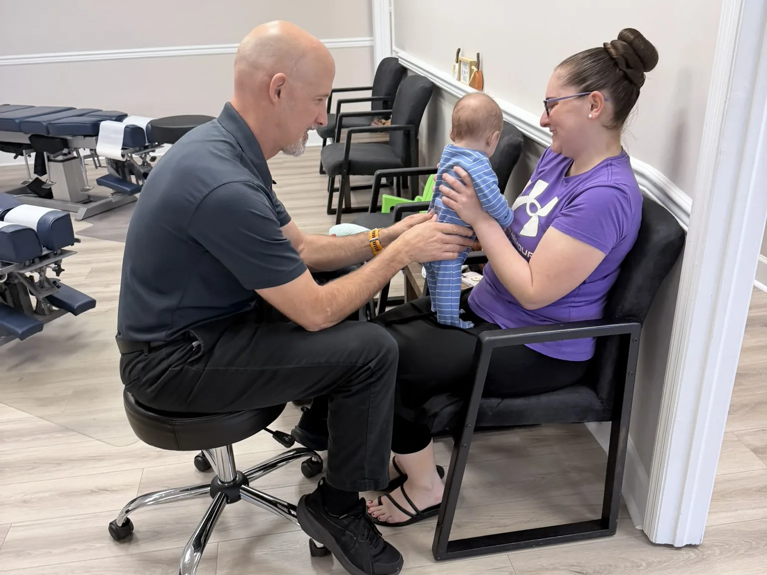 Dr. Jon Scott gently checking an infant on a parent’s lap