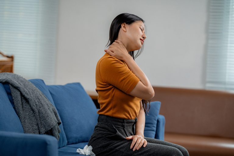 A woman grimacing while holding her sore neck, seeking professional neck pain relief in Knoxville TN from a leading chiropractor in Knoxville.